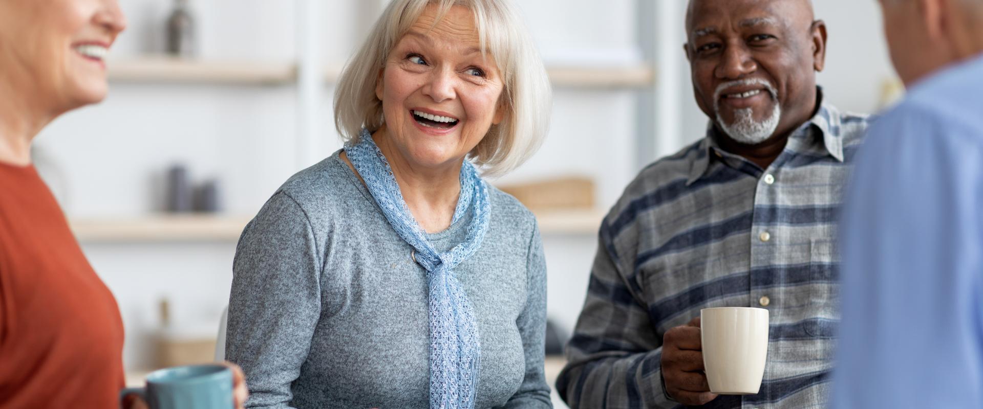 Paciente idosa sorridente conversando com fonoaudióloga em consultório acolhedor, ambos sentados próximos, luz natural suave, clima de confiança e cuidado, fotografia realista